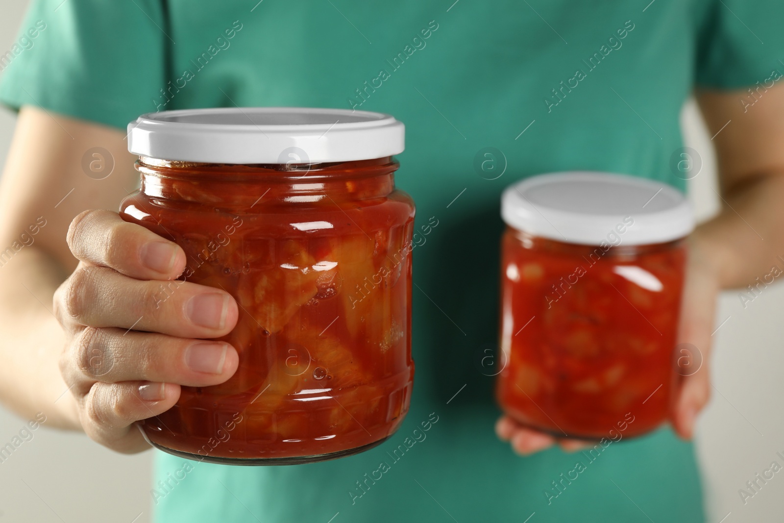 Photo of Woman holding jars of canned lecho, closeup