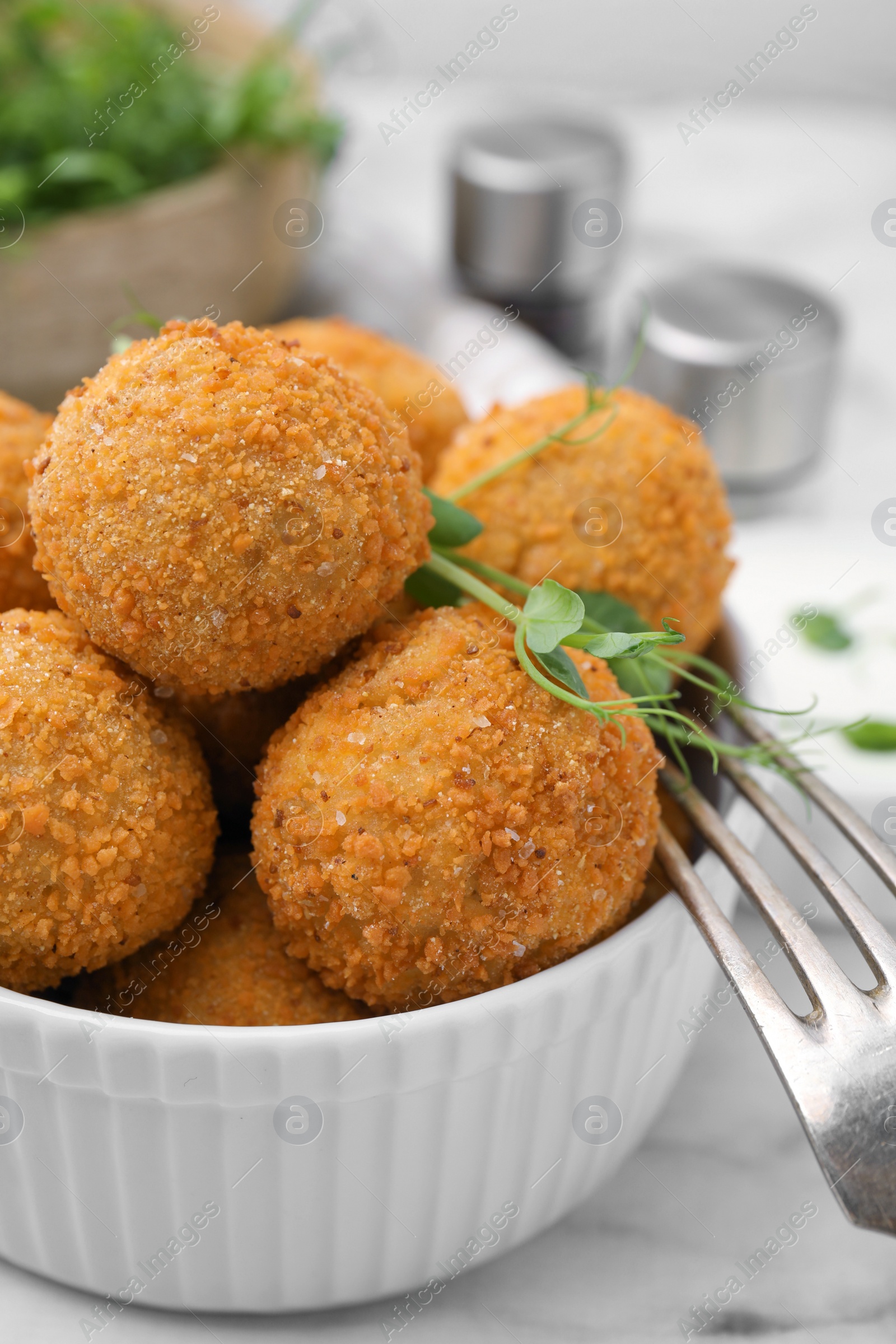 Photo of Bowl of delicious fried tofu balls with pea sprouts on white marble table, closeup