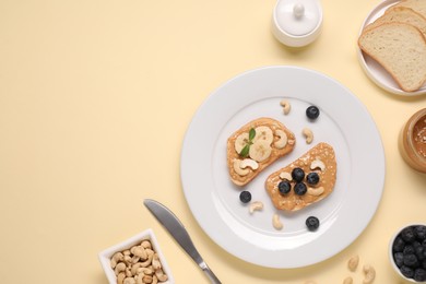 Photo of Toasts with tasty nut butter, blueberries and cashews on beige background, flat lay. Space for text