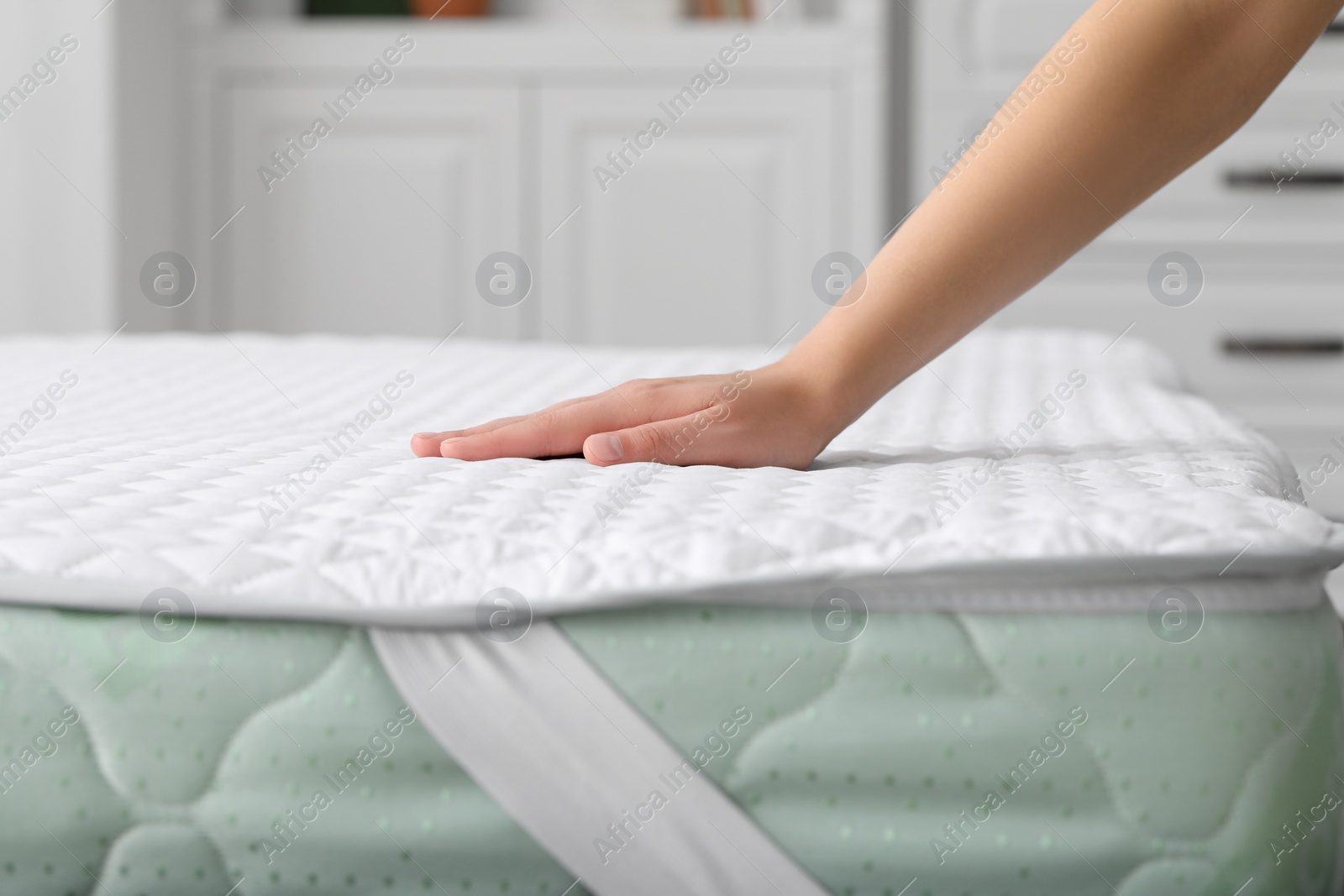 Photo of Woman touching new soft mattress in bedroom, closeup