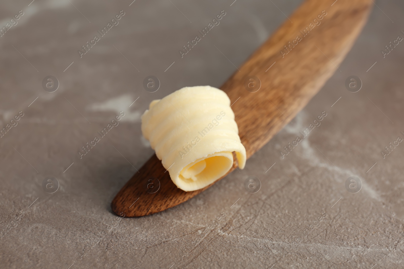 Photo of Wooden knife with butter curl on table