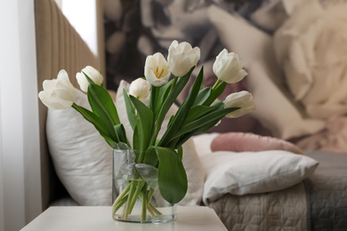 Photo of Vase with white tulips on table in bedroom. Interior element