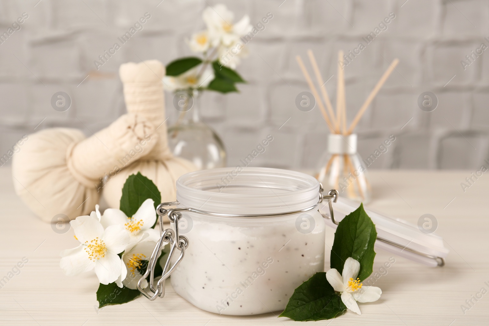 Photo of Jar of salt scrub and beautiful jasmine flowers on white wooden table