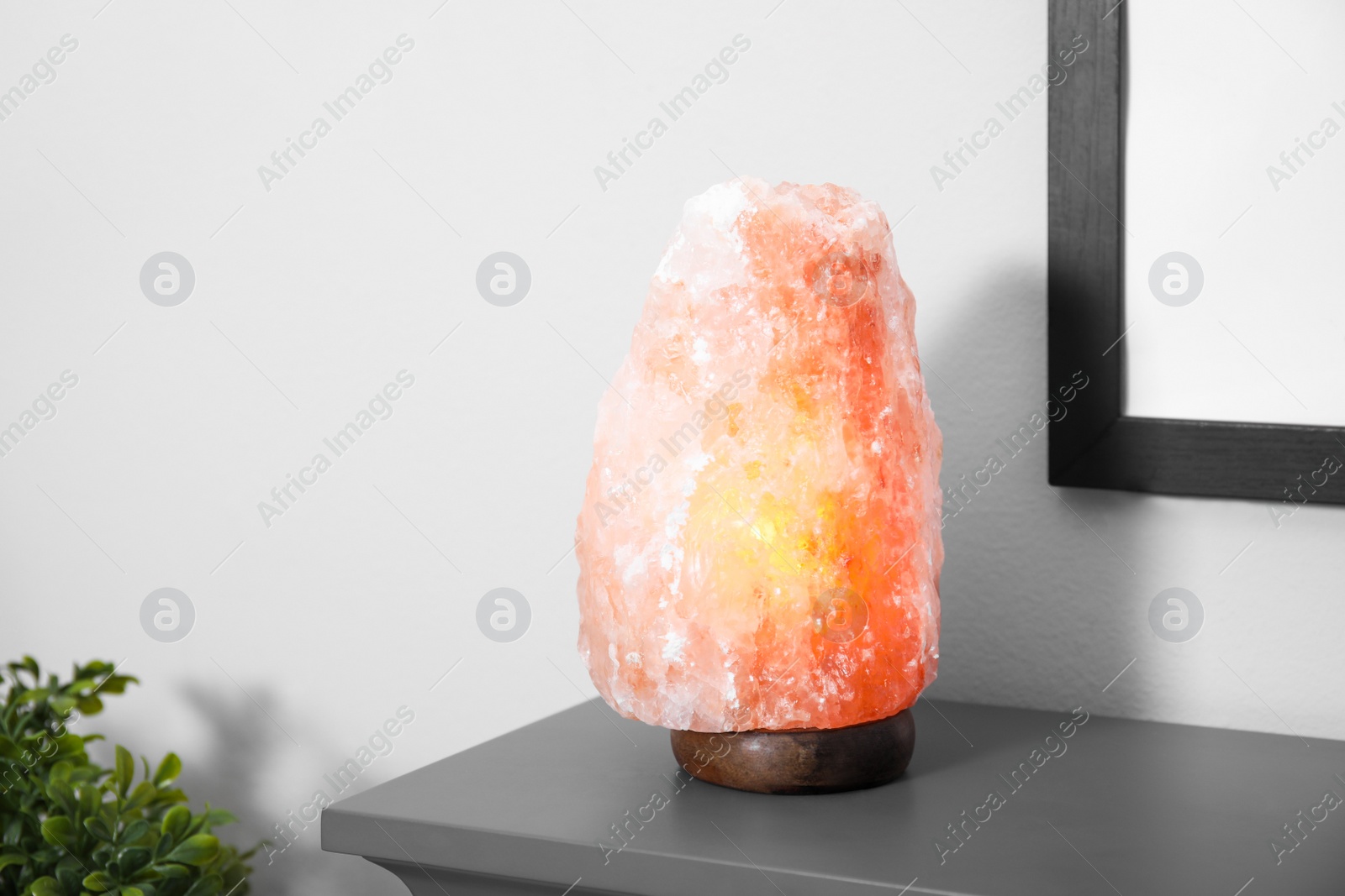 Photo of Himalayan salt lamp on grey console table near wall in room. Space for text