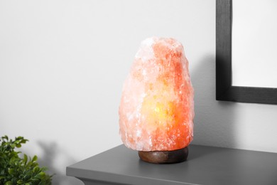 Photo of Himalayan salt lamp on grey console table near wall in room. Space for text