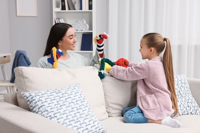 Happy mother and daughter playing with sock puppets together at home