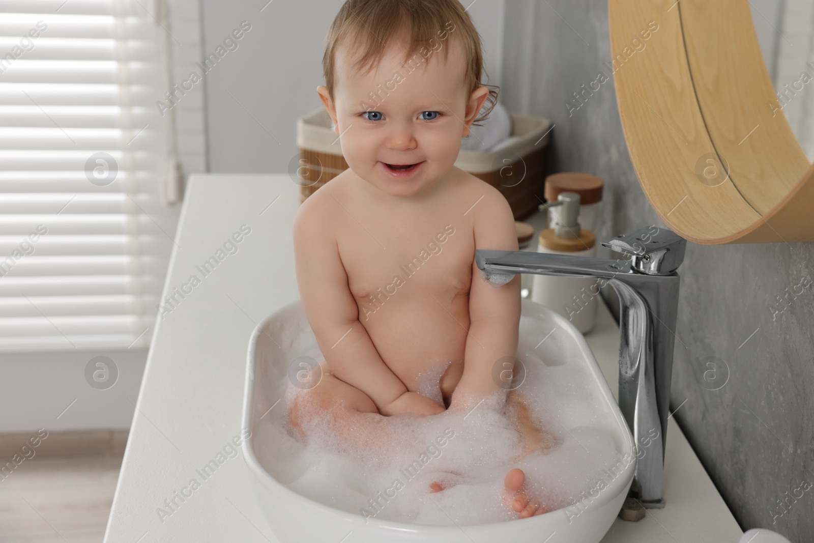 Photo of Cute little baby bathing in sink at home