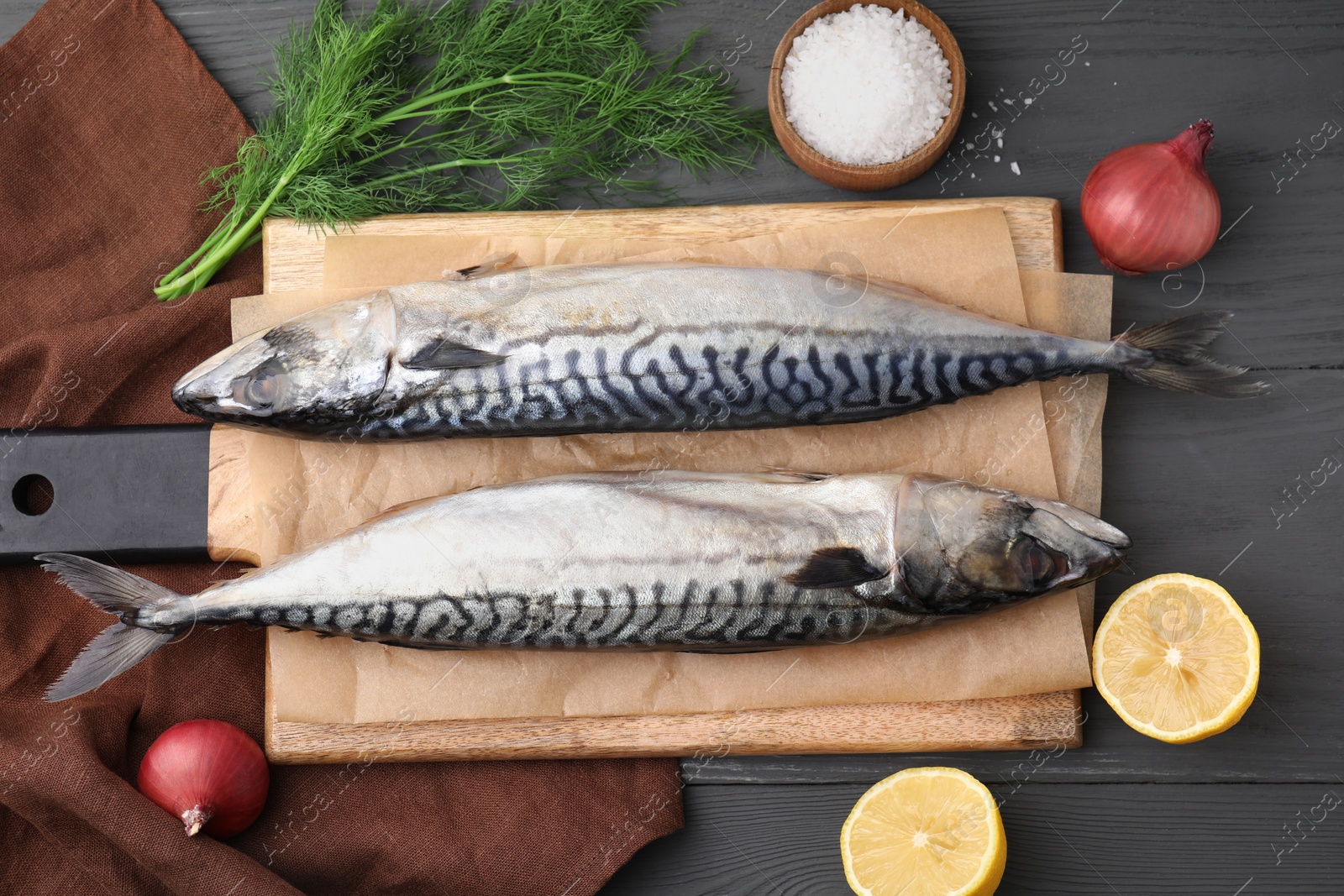 Photo of Tasty salted mackerels and products on gray wooden table, flat lay