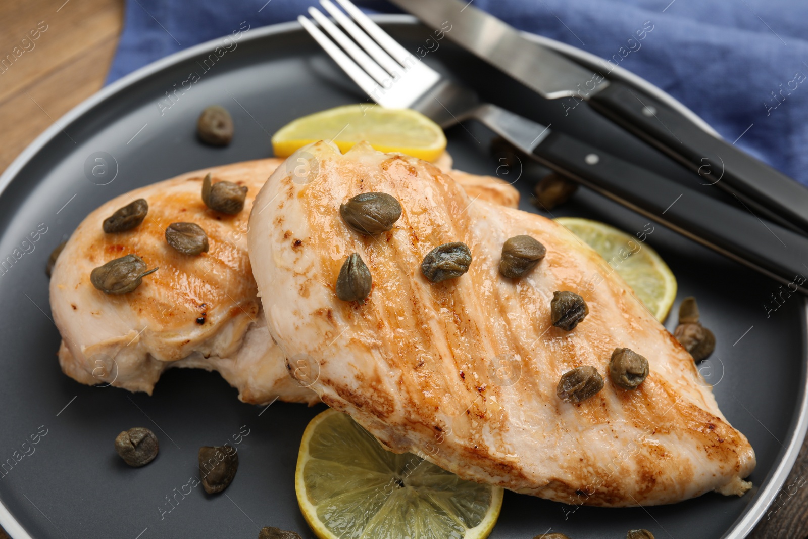 Photo of Delicious chicken fillets with capers and lemon on plate, closeup