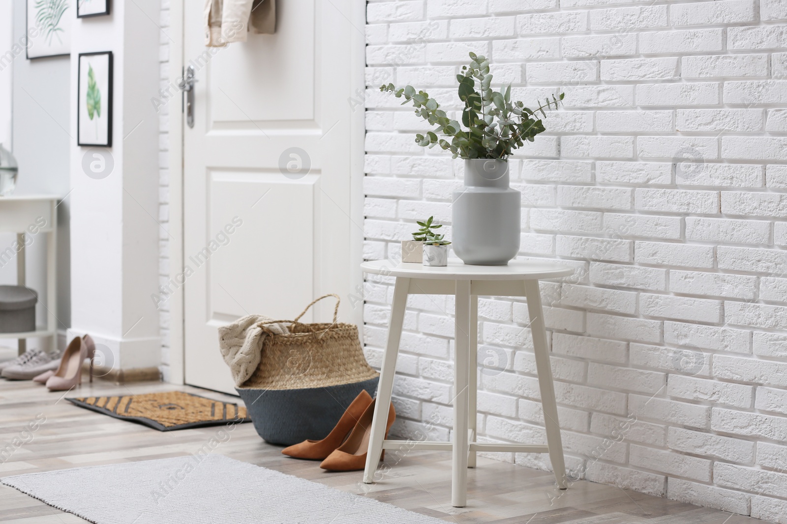 Photo of Vase with fresh eucalyptus branches on table in entryway. Interior design