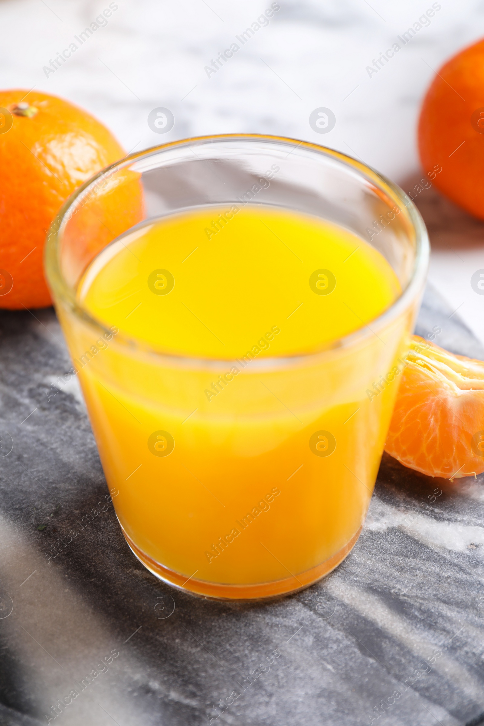 Photo of Glass of fresh tangerine juice and fruits on board