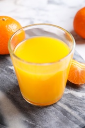 Photo of Glass of fresh tangerine juice and fruits on board