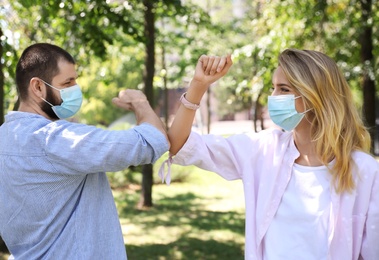 Photo of Man and woman bumping elbows to say hello outdoors. Keeping social distance during coronavirus pandemic