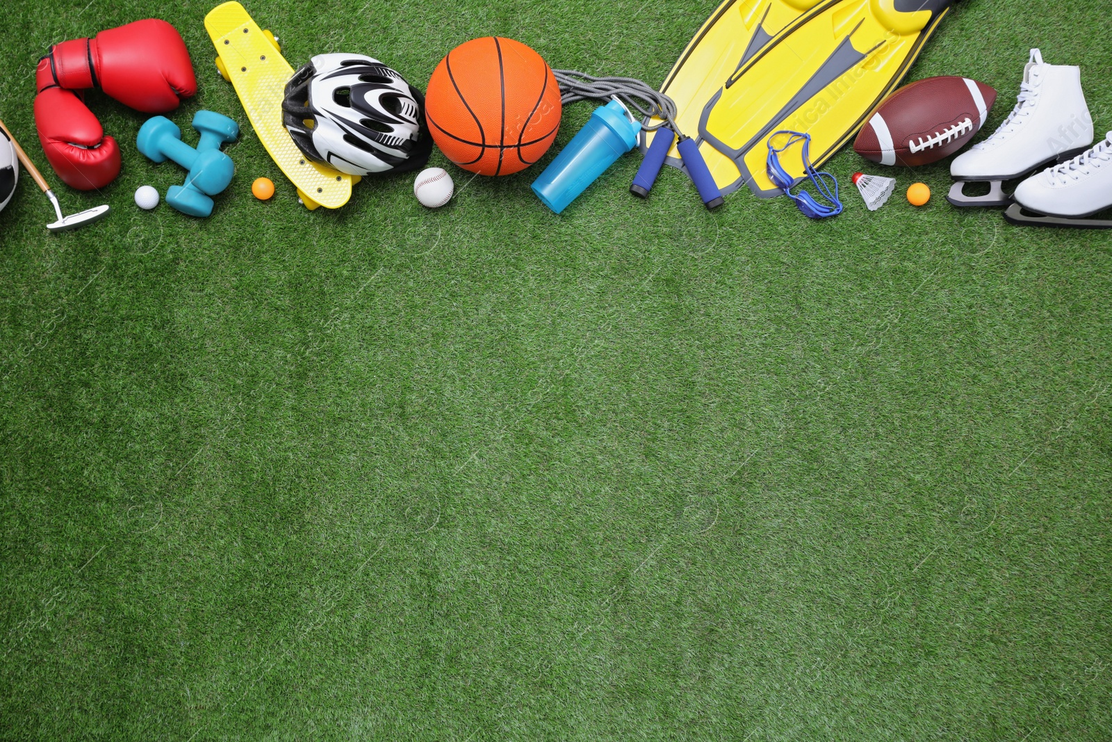 Photo of Different sport equipment on green grass, flat lay. Space for text