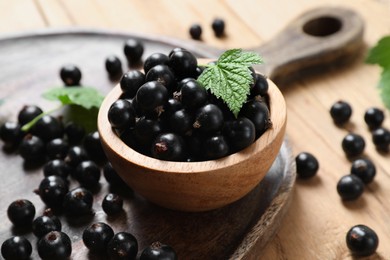 Ripe blackcurrants and leaves on wooden table, closeup