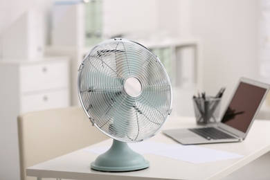 Photo of Modern electric fan on table in office