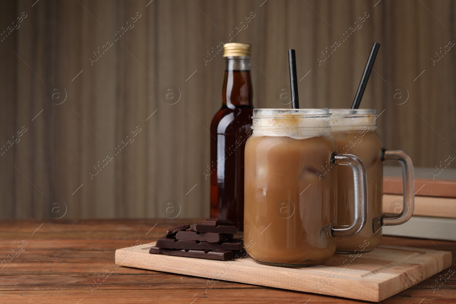 Photo of Delicious iced coffee with chocolate syrup on wooden table, space for text