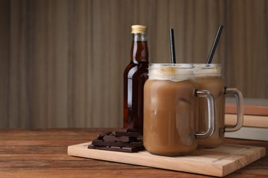 Delicious iced coffee with chocolate syrup on wooden table, space for text