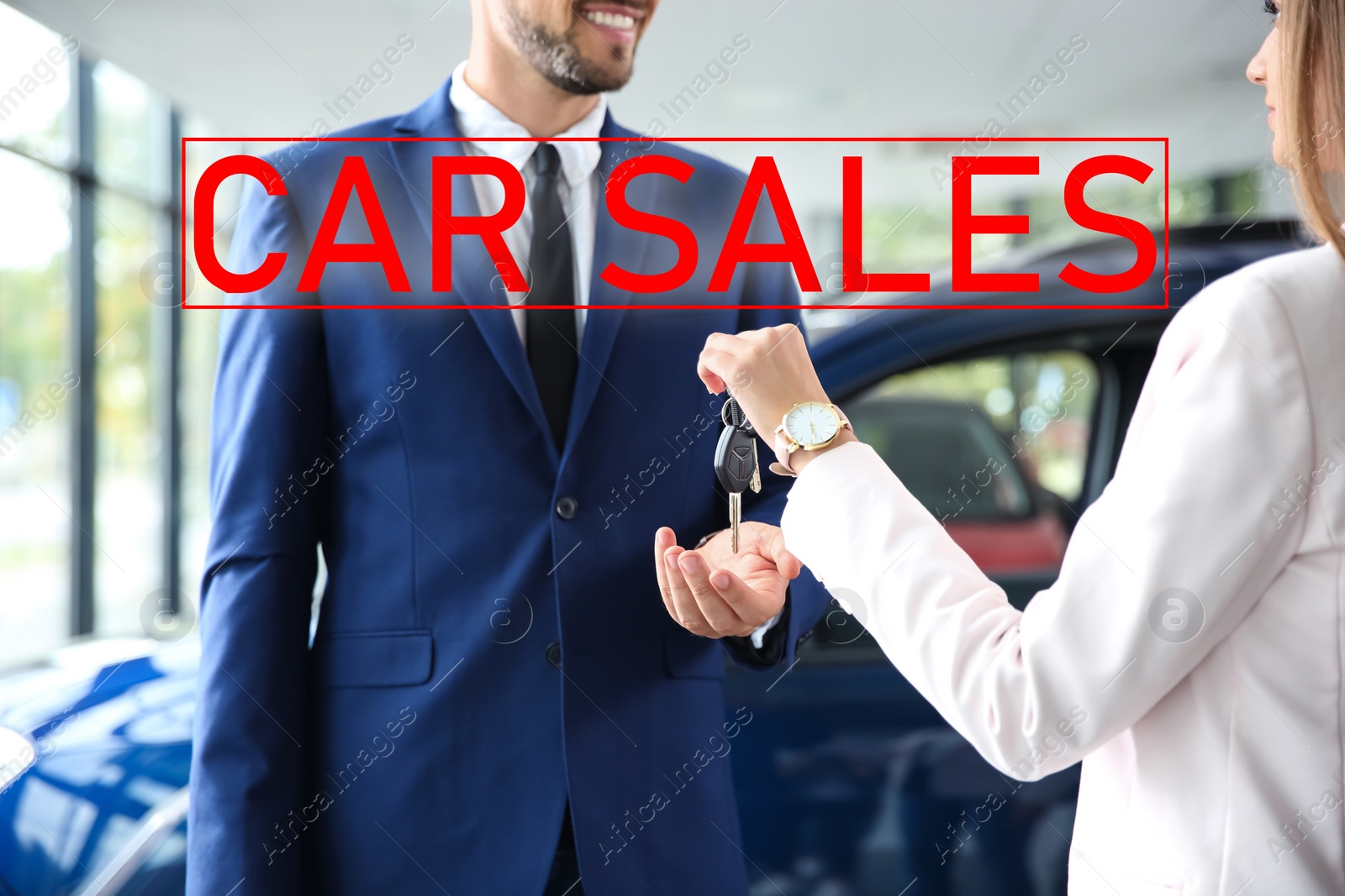 Image of Salesperson giving car keys to man in auto dealership, closeup