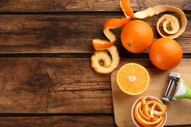 Photo of Orange fruits with peels on wooden table, flat lay. Space for text