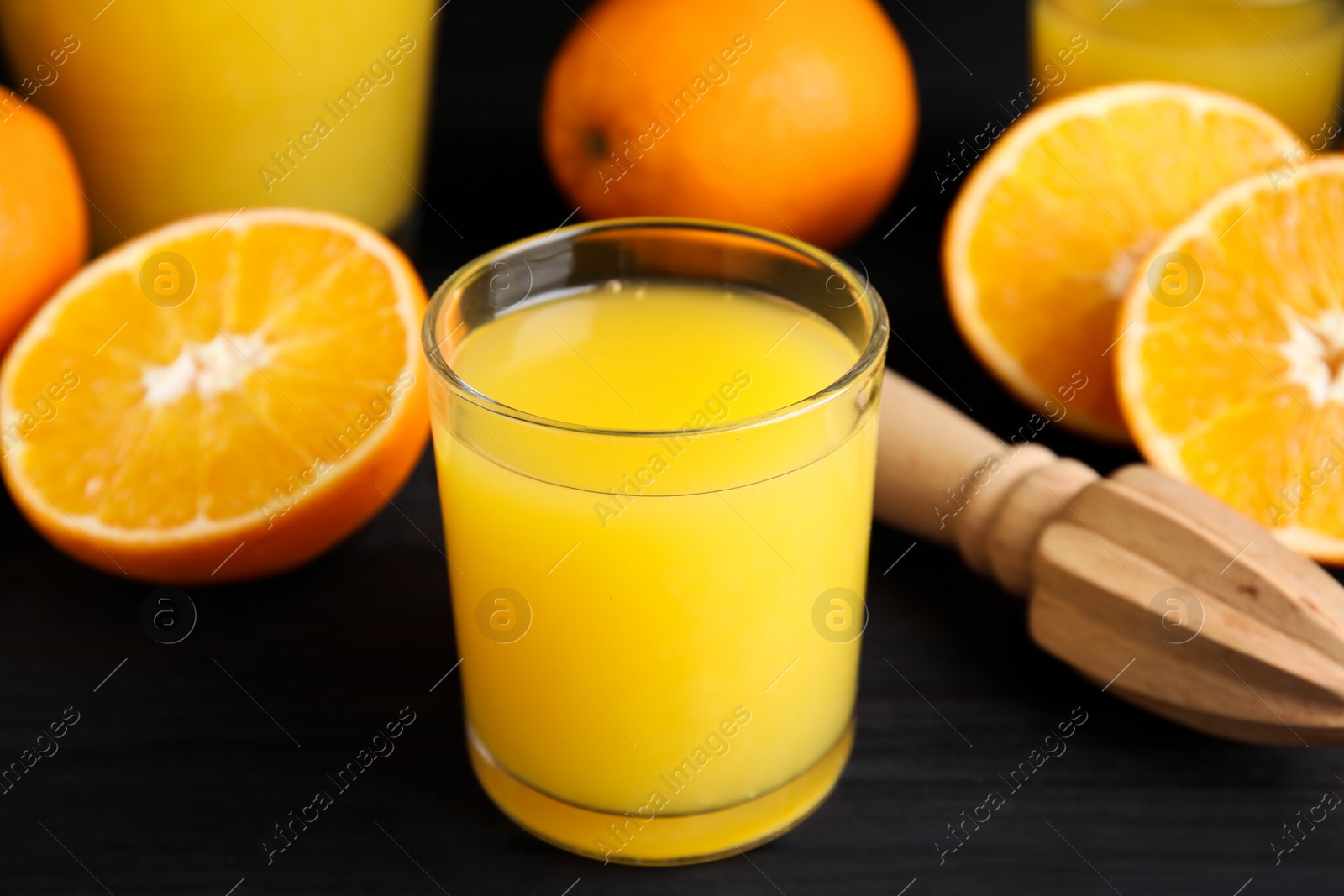 Photo of Fresh ripe oranges, juice and reamer on dark wooden table, closeup