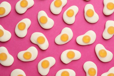 Photo of Tasty jelly candies in shape of egg on pink background, flat lay
