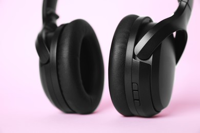 Photo of Modern wireless headphones on pink background, closeup
