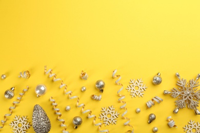 Photo of Flat lay composition with serpentine streamers and Christmas decor on yellow background. Space for text