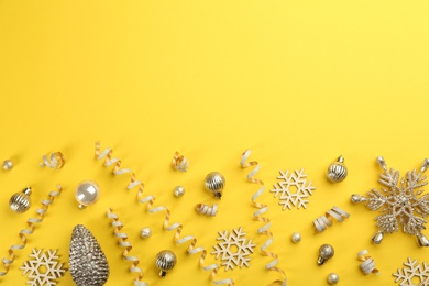 Flat lay composition with serpentine streamers and Christmas decor on yellow background. Space for text