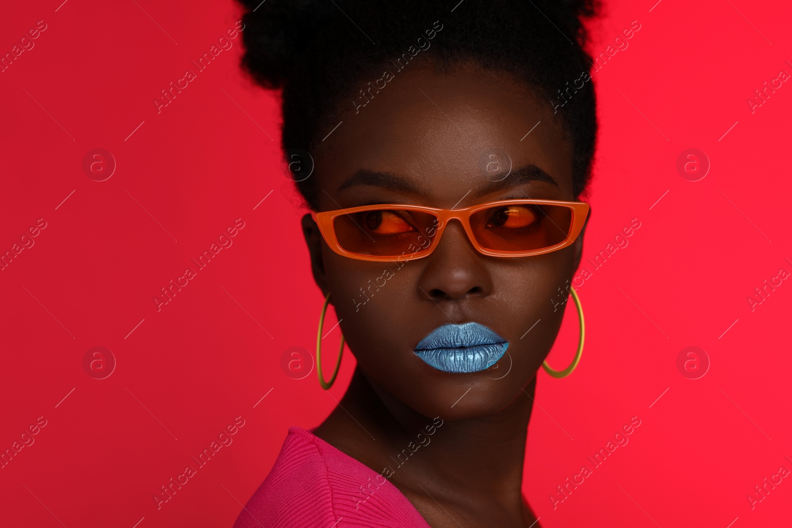 Photo of Fashionable portrait of beautiful woman with stylish sunglasses on coral background