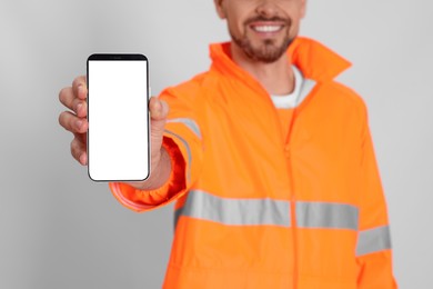 Man in reflective uniform with phone on white background, closeup