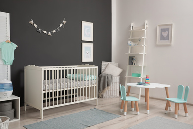 Photo of Cute baby room interior with modern crib near dark wall