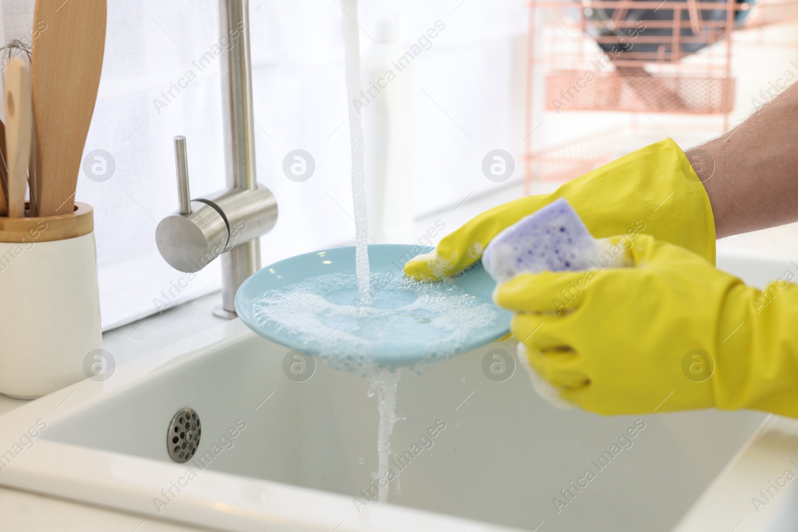 Photo of Man washing plate above sink in kitchen, closeup