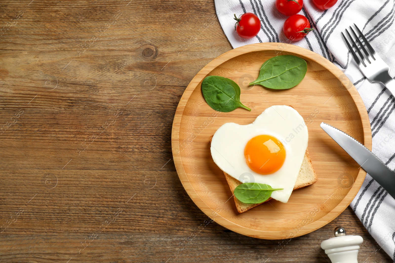 Photo of Tasty fried egg in shape of heart with toast served on wooden table, flat lay. Space for text