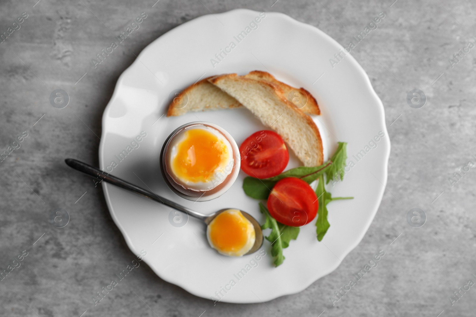 Photo of Breakfast with soft boiled egg on grey table, top view