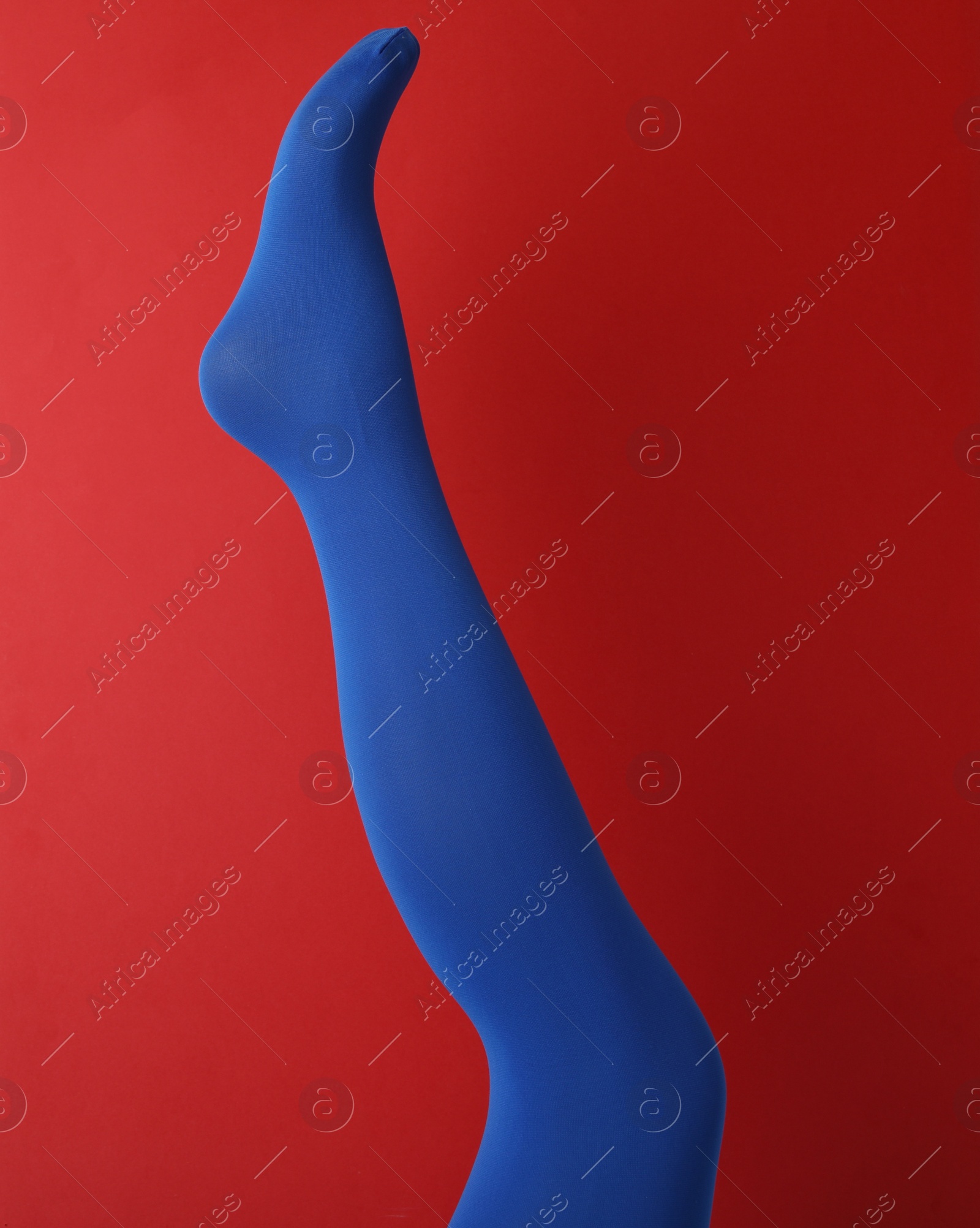 Photo of Leg mannequin in blue tights on red background