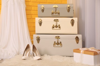 Photo of Storage trunks, shoes and gift box near yellow brick wall indoors. Interior design