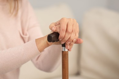 Photo of Mature woman with walking cane on blurred background, closeup