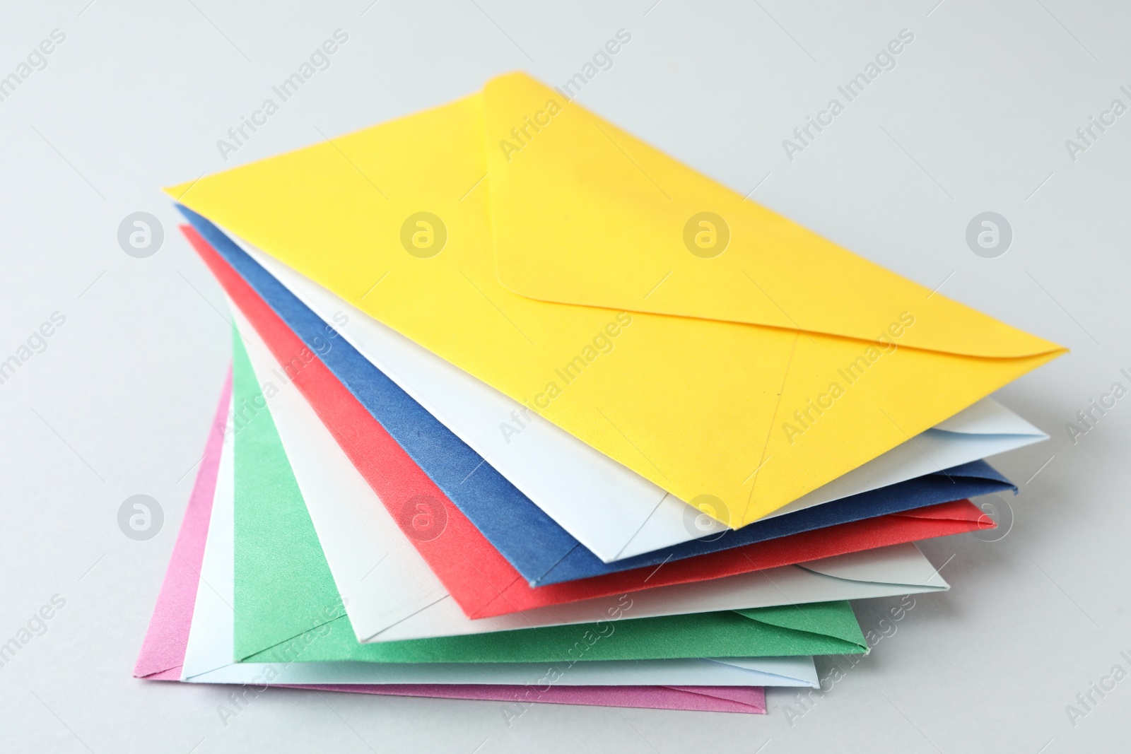 Photo of Stack of colorful paper envelopes on light background