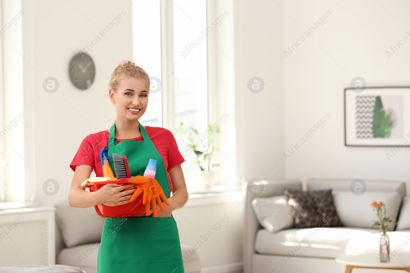 Photo of Woman with basin and cleaning supplies in living room