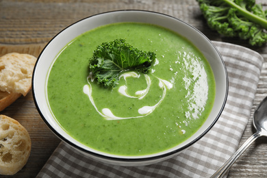 Photo of Tasty kale soup with cream on wooden table