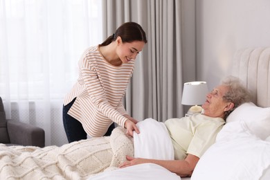 Photo of Young caregiver and senior woman in bedroom. Home health care service