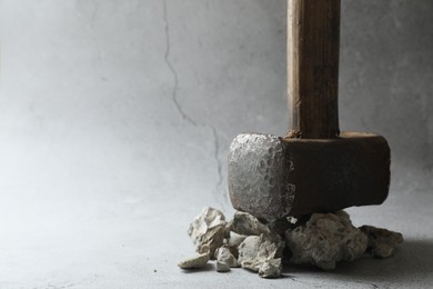 One sledgehammer and pieces of broken stones on grey background, closeup. Space for text