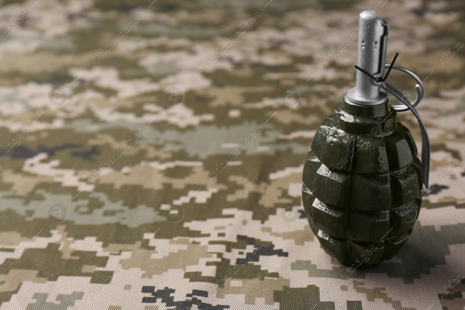 Photo of Hand grenade on digital camouflage fabric. Space for text