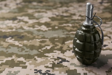 Photo of Hand grenade on digital camouflage fabric. Space for text