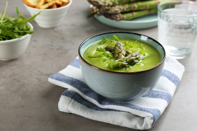 Delicious asparagus soup served on grey table