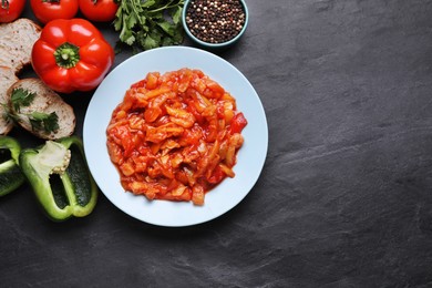 Photo of Delicious lecho and ingredients on black table, flat lay. Space for text