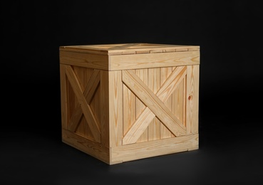 Photo of One closed wooden crate on black background