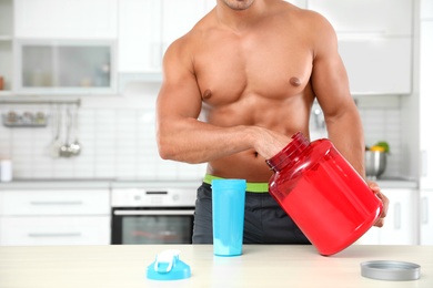 Photo of Young athletic man preparing protein shake in kitchen, closeup view. Space for text