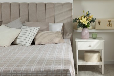 Photo of Bouquet of beautiful flowers on nightstand in bedroom